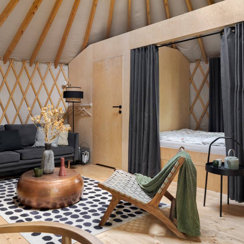 Intérieur de la yourte salon cosy avec canapé, vue sur la chambre