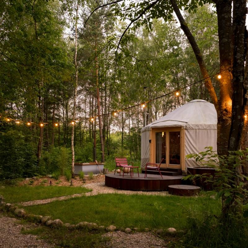 Yourte moderne avec une terrasse dans la forêt illuminée la nuit